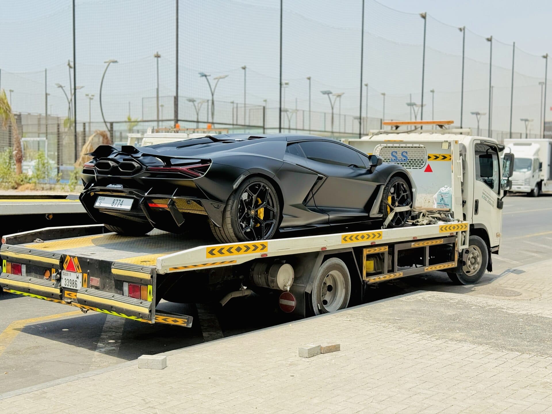 TAS Car Towing flatbed truck carrying a black Lamborghini Revuelto in Dubai