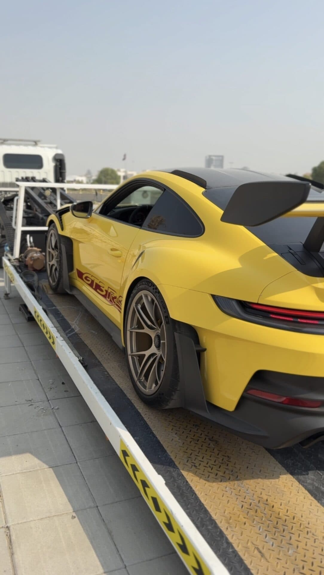 TAS Car Towing flatbed truck carrying a yellow Porsche 911 GT3 RS in Dubai