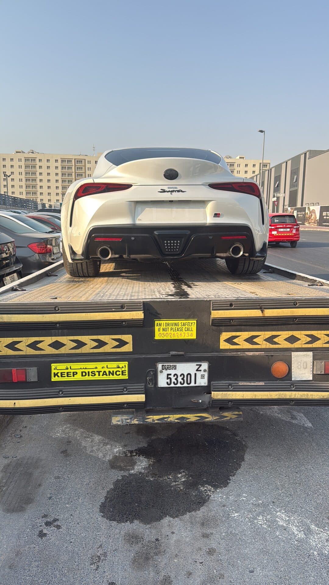 TAS Car Towing flatbed recovery truck carrying a white Toyota Supra in Dubai